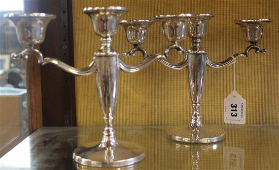 A pair of 1950s silver two branch three light candelabra, weighted.